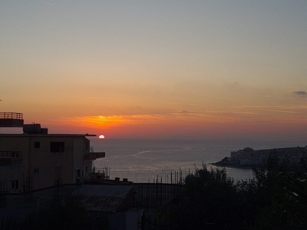 Sunset over the Ionian Sea in Sarandë, Albania with coastal silhouette