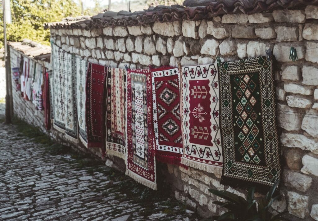 Traditional Albanian rugs hanging on a stone wall in Berat