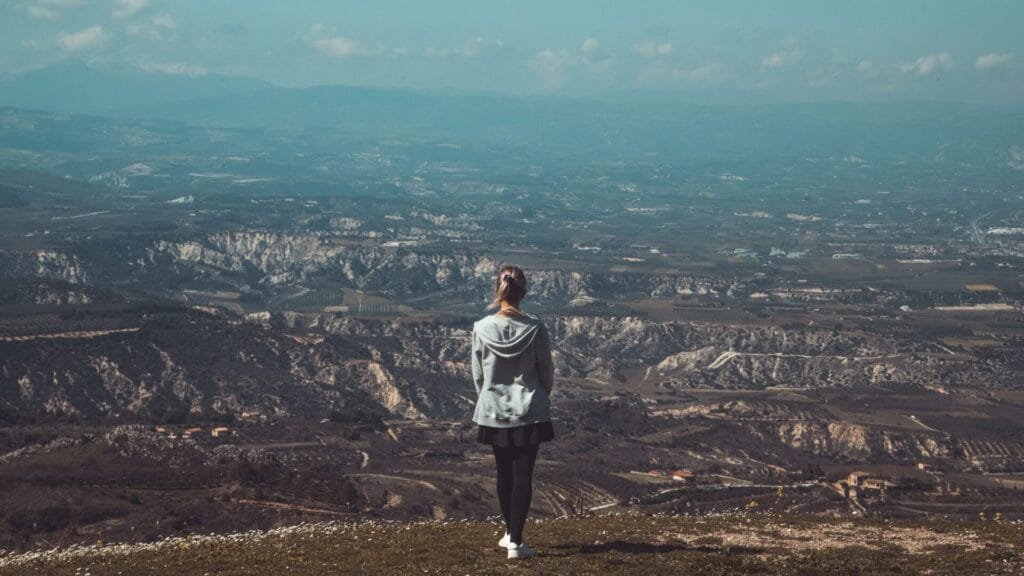 Person standing with a scenic mountain landscape in the background