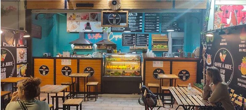 Cozy interior of a small Albanian juice bar with seating and a menu board